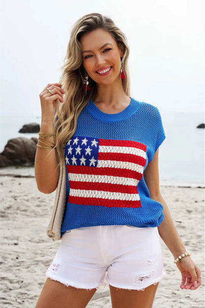 Woman wearing a blue sweater with an American flag design on a beach.