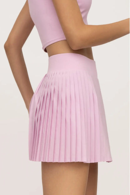 Person wearing a pink pleated skirt on a light gray background