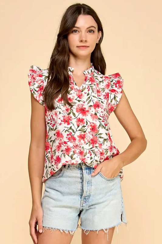 Woman wearing a floral top and denim shorts on a beige background