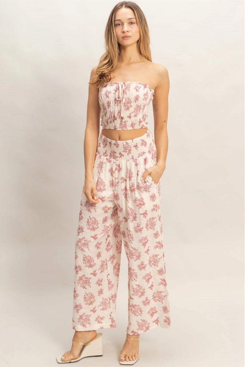 Woman wearing a pink floral jumpsuit on a plain background