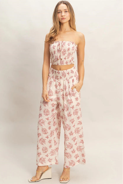 Woman wearing a pink floral jumpsuit on a plain background