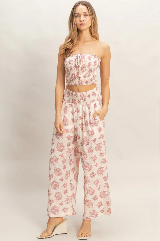 Woman wearing a pink floral jumpsuit on a plain background