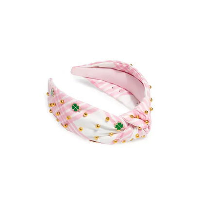 Pink and white headband with gold beads and green clover patterns on a white background