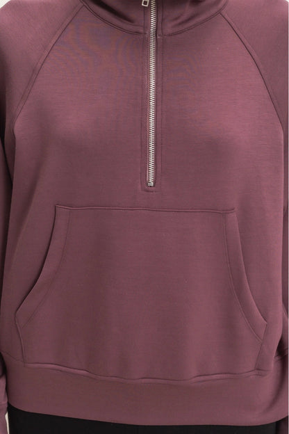 A close-up of a mauve-colored half-zip pullover hoodie with a front kangaroo pocket and a silver zipper, shown on a plain white background.