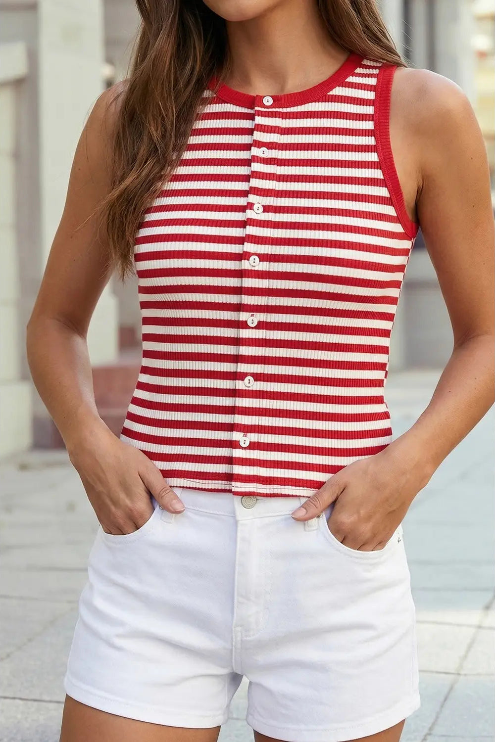 Person wearing a red and white striped sleeveless top with buttons, paired with white shorts.