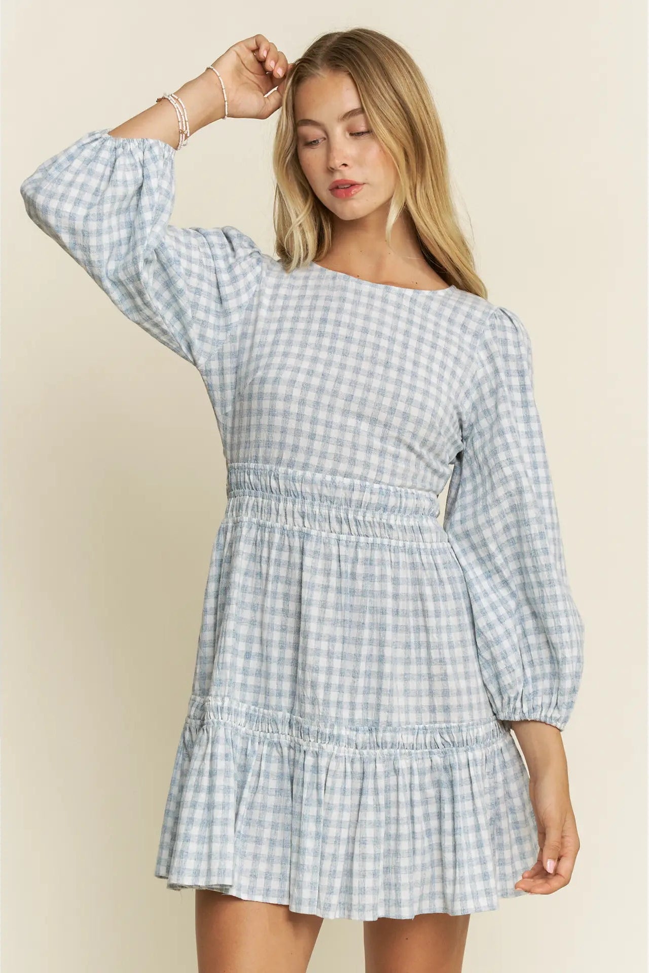 Woman wearing a blue and white checkered dress against a beige background