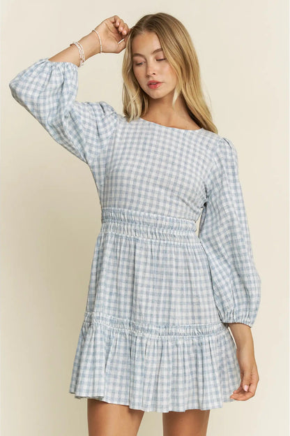 Woman wearing a blue and white checkered dress against a beige background