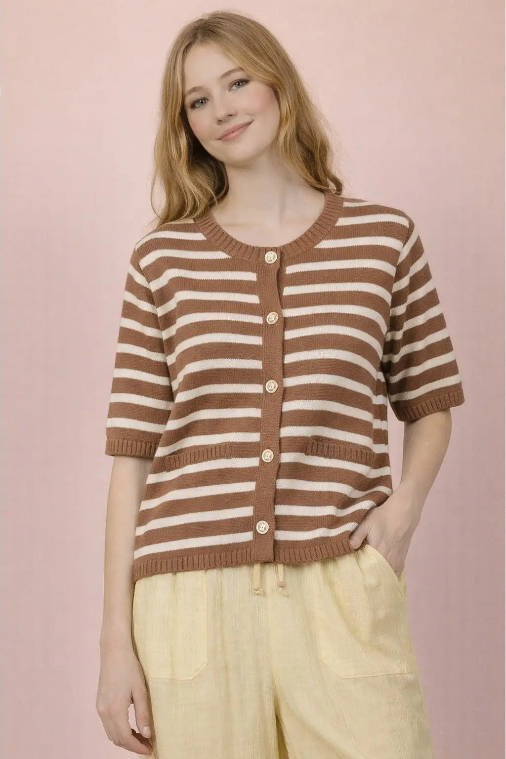 Woman wearing a brown and white striped sweater against a pink background