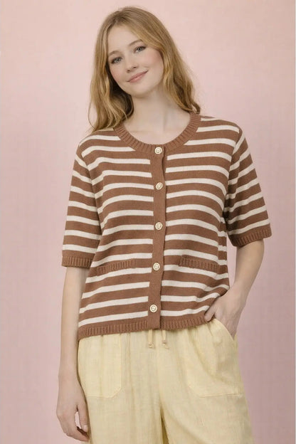 Woman wearing a brown and white striped sweater against a pink background