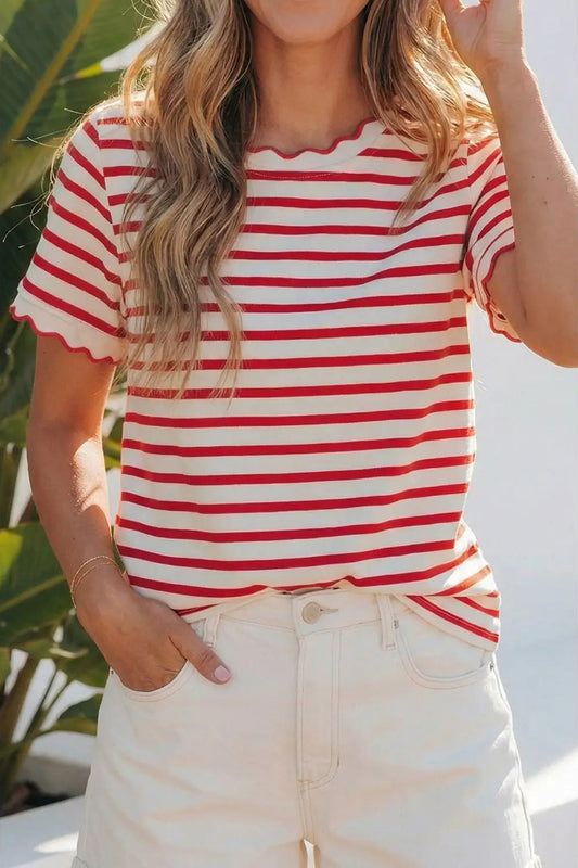 Person wearing a red and white striped shirt with white pants, standing outdoors.