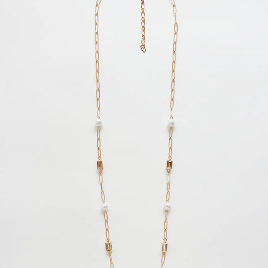 Gold chain necklace with small pearls on a light gray background