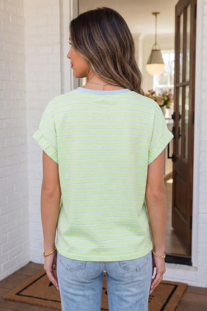 Woman wearing a light green and white striped t-shirt and blue jeans indoors.
