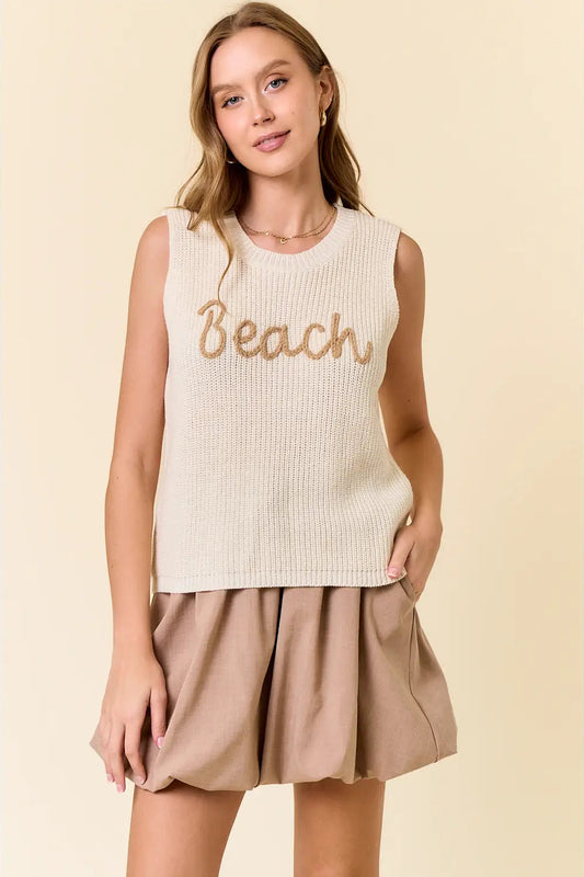 Woman wearing a beige sleeveless top with 'Beach' text and beige shorts on a beige background