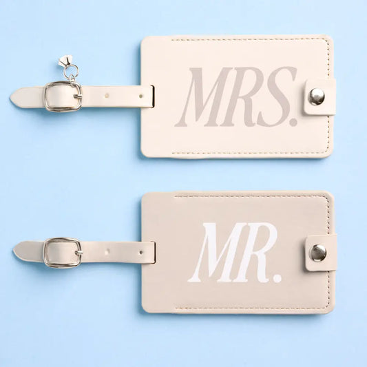 Pair of beige luggage tags with 'MR.' and 'MRS.' text on a light blue background