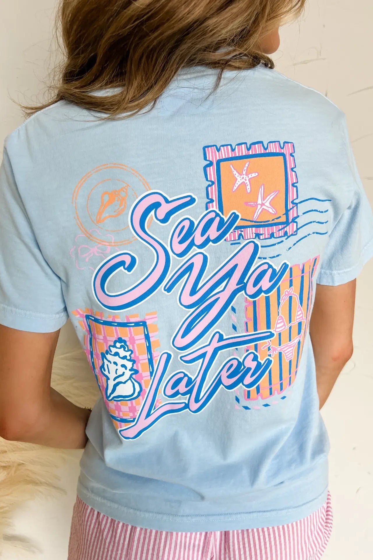 Light blue t-shirt with colorful graphics and text on a neutral background