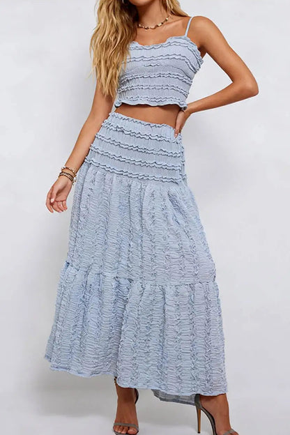 Woman wearing a light blue ruffled top and skirt set on a white background