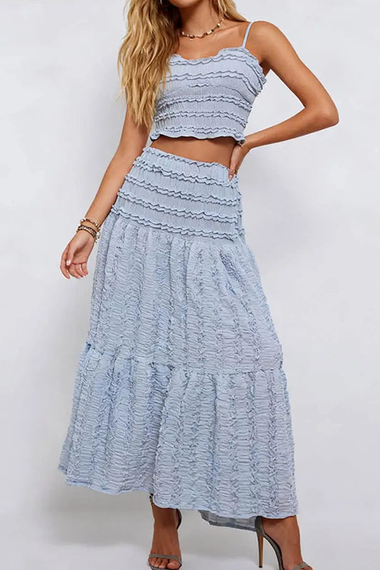 Woman wearing a light blue ruffled top and skirt set on a white background