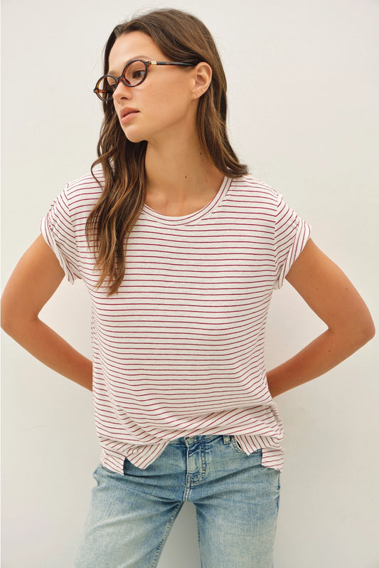 Woman wearing a striped shirt and jeans against a plain background