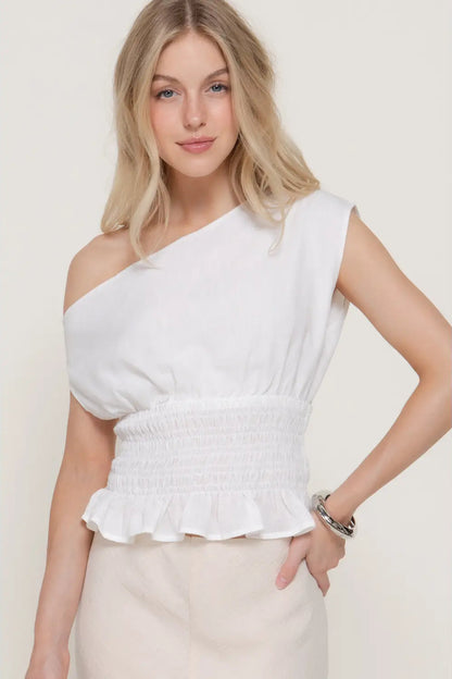 Woman wearing a white one-shoulder top against a plain background