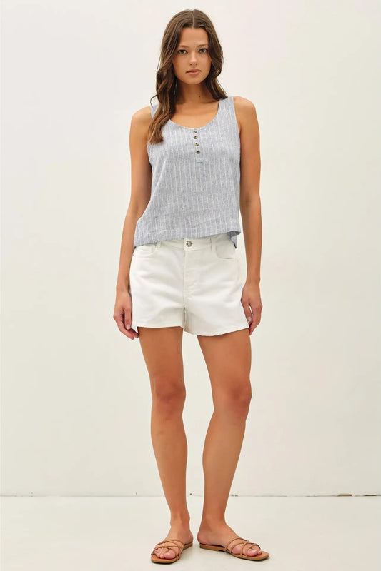 Woman wearing a light blue sleeveless top and white shorts on a white background