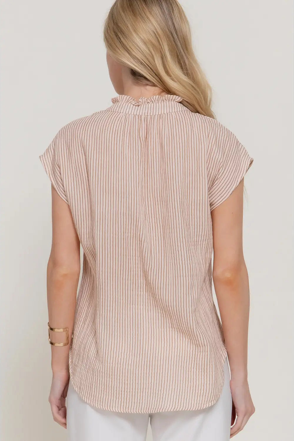 Woman wearing a beige ribbed sleeveless top against a white background