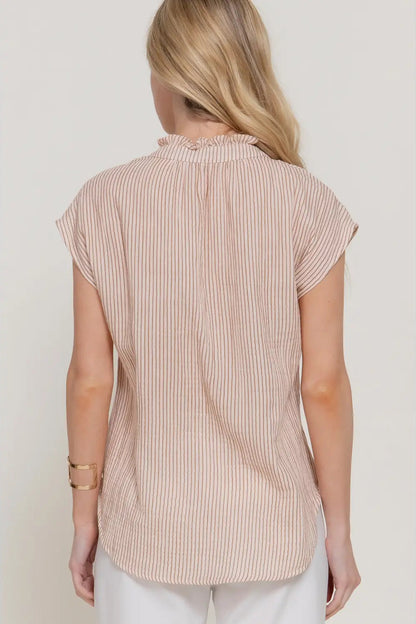 Woman wearing a beige ribbed sleeveless top against a white background