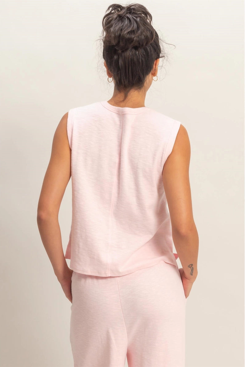 Person wearing a light pink sleeveless top and pants on a plain background