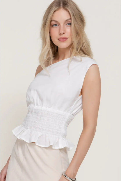 Woman wearing a white one-shoulder top against a plain background