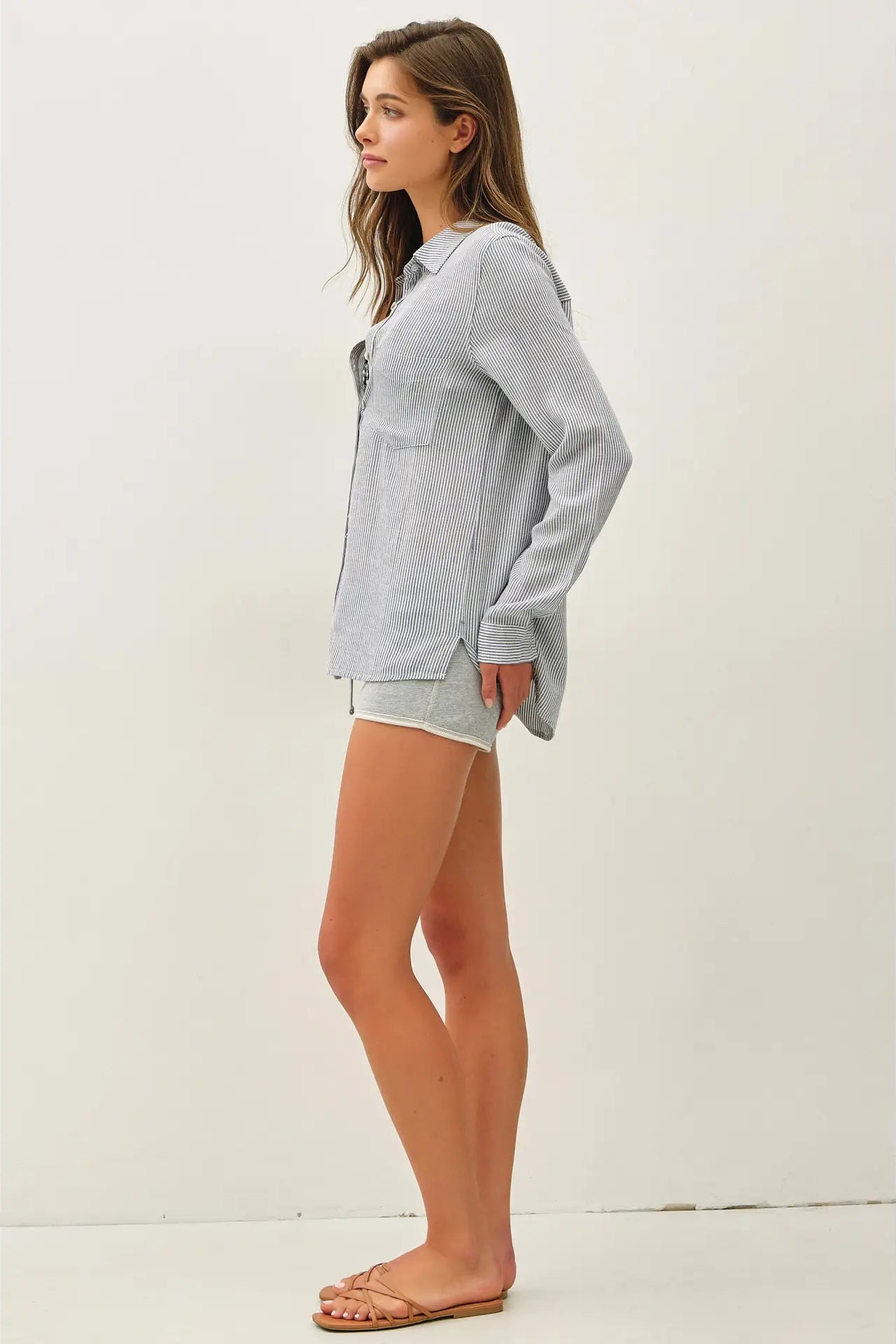 Woman wearing a light gray oversized shirt and shorts on a white background