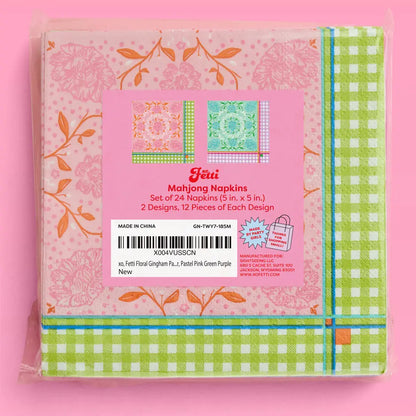 A packaged set of Fetti Mahjong Napkins in a pink plastic bag, featuring floral and gingham patterns in green, pink, orange, and blue, with a pink label in the center.