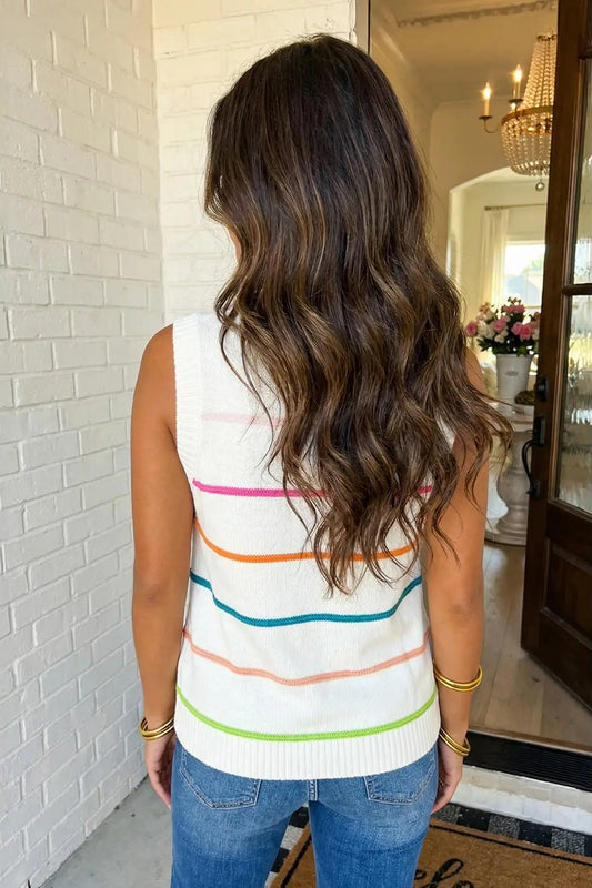 Woman wearing a colorful striped sleeveless sweater in a home setting.