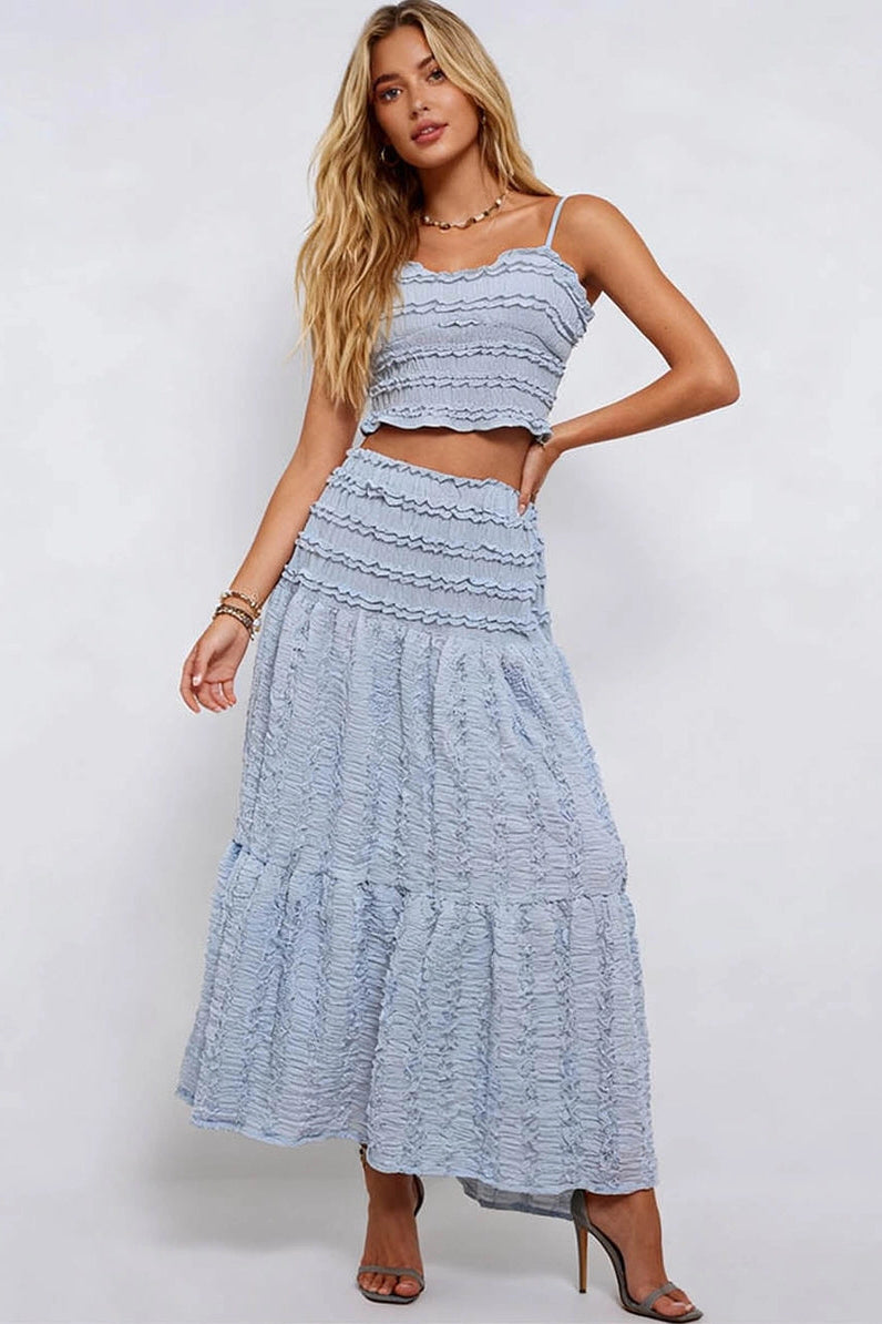 Woman wearing a light blue dress with ruffled layers on a white background
