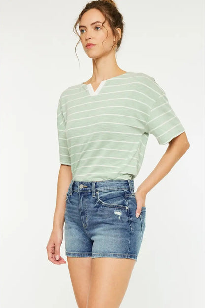 Woman wearing a striped shirt and denim shorts on a white background