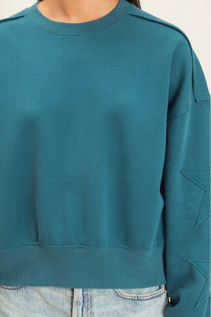 person wearing sweatshirt with stars on the sleeve