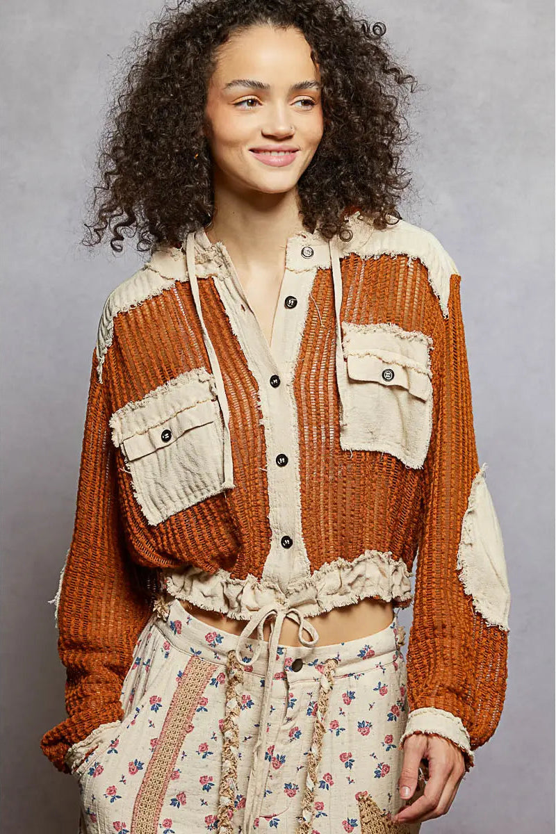 Woman wearing a patterned outfit with a textured brown jacket against a gray background