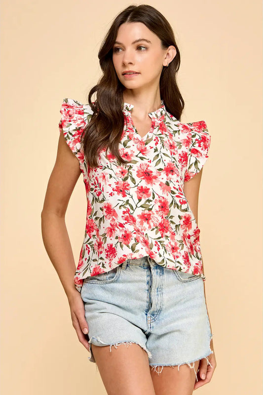 Woman wearing a floral top and denim shorts on a beige background