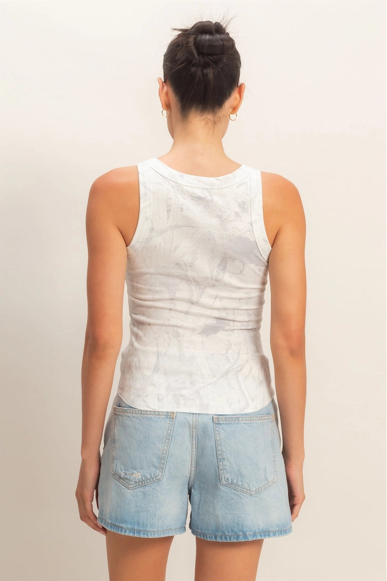 Person wearing a white sleeveless top and denim shorts on a plain background