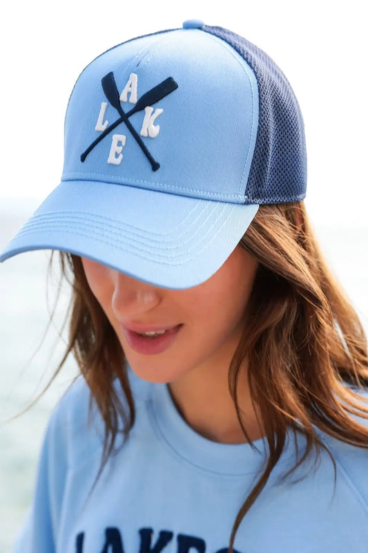 Light blue cap with 'LAKE' design worn by a person against a white background