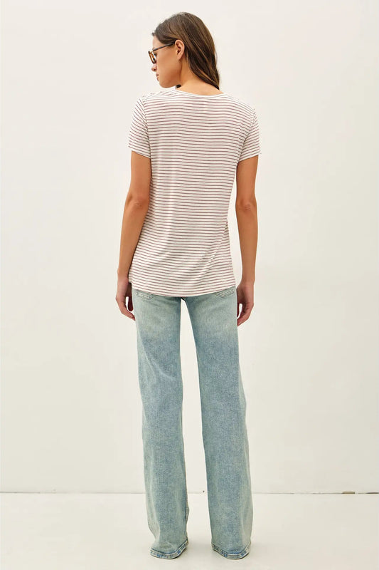 Woman wearing a striped shirt and light blue jeans against a white background
