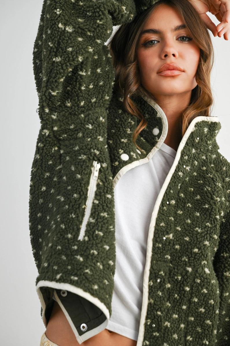 Woman wearing a green fleece jacket with white accents on a plain background