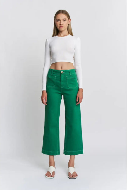 Woman wearing a white crop top and green pants on a white background