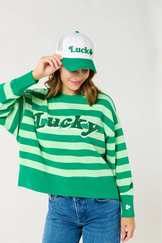 Person wearing a green and white striped sweater and cap with 'Lucky' text on a plain background