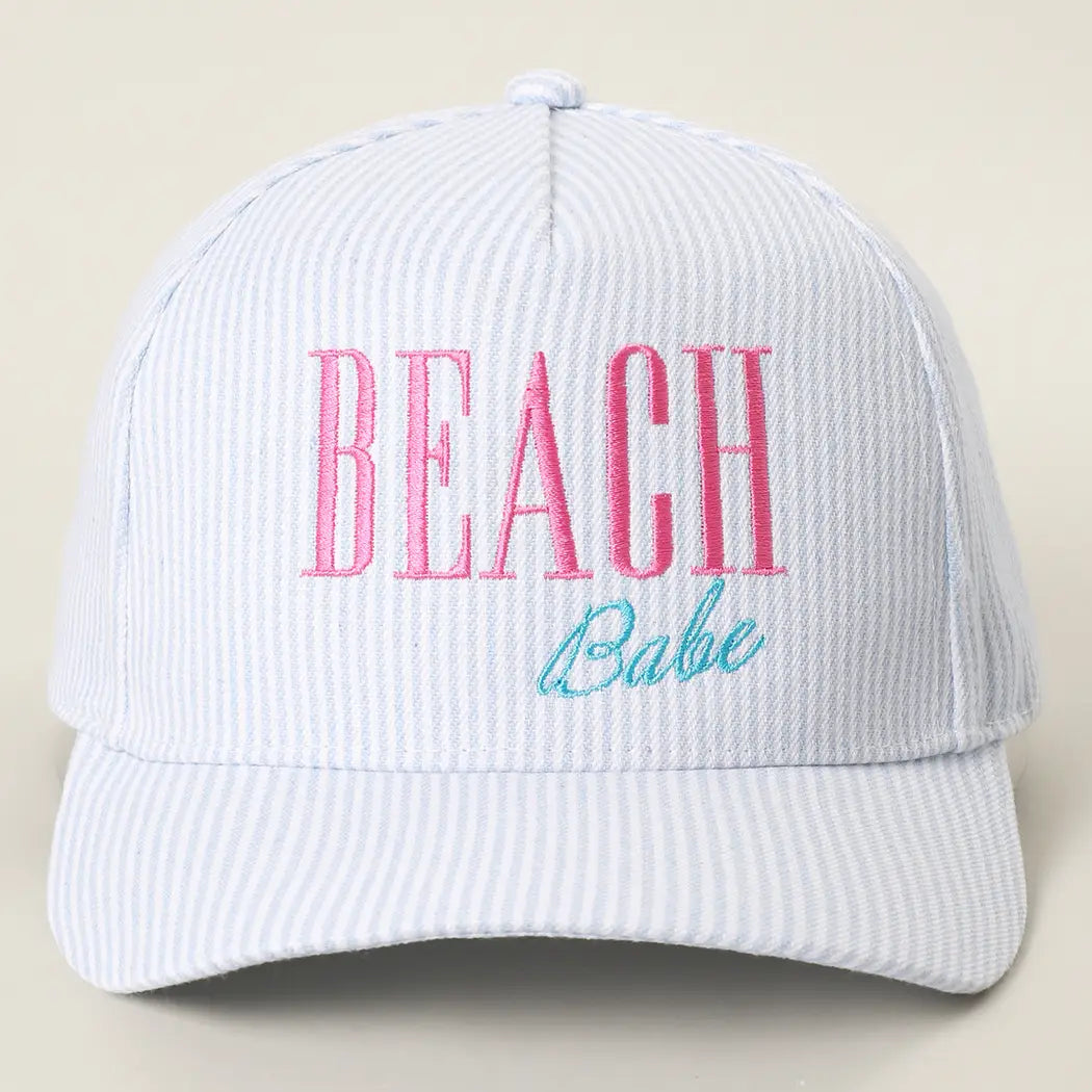 White cap with 'BEACH Babe' text in pink and blue on a beige background