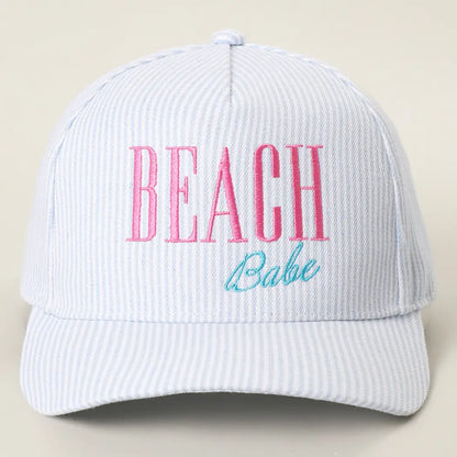 White cap with 'BEACH Babe' text in pink and blue on a beige background