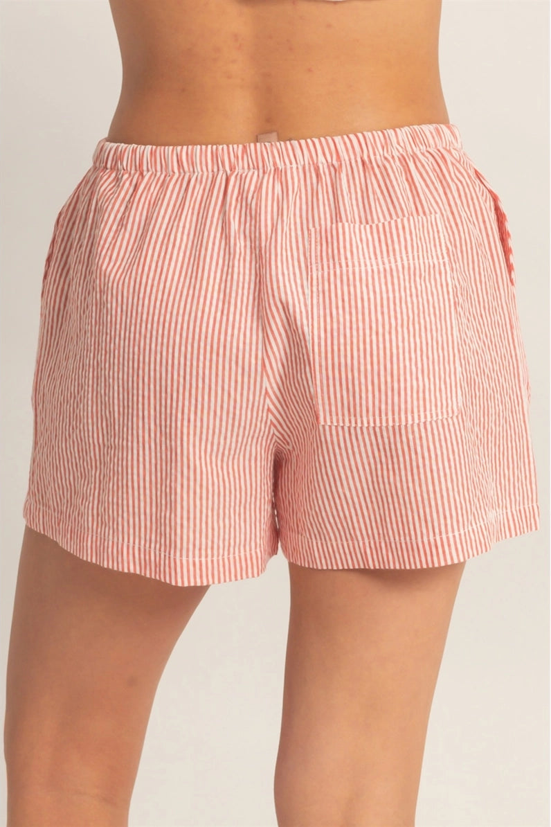Pink striped shorts worn by a person on a plain background