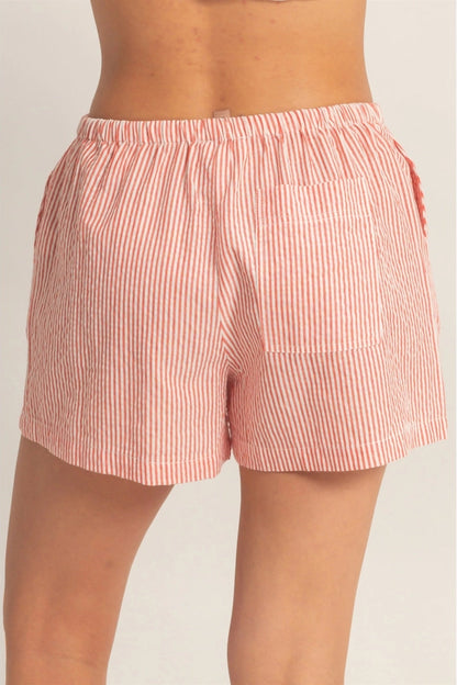 Pink striped shorts worn by a person on a plain background