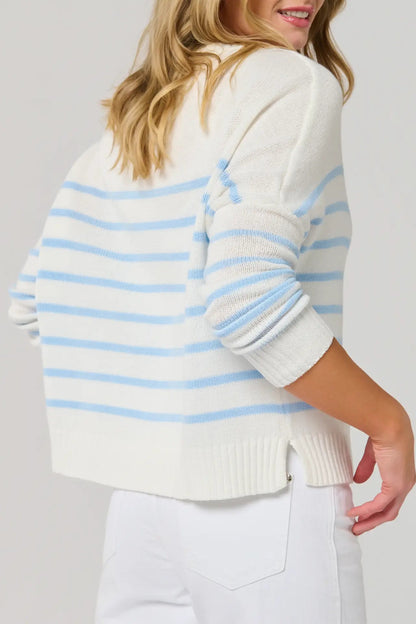 Woman wearing a white sweater with blue stripes on a plain background