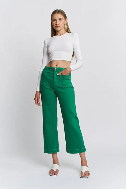 Woman wearing a white long-sleeve top and green pants on a white background