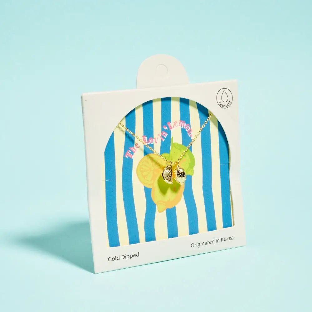 Necklace with a green leaf pendant in a striped packaging on a light blue background