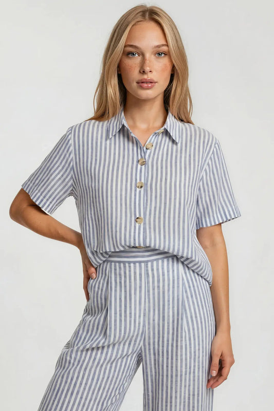 Woman wearing a blue and white striped shirt and pants on a light gray background